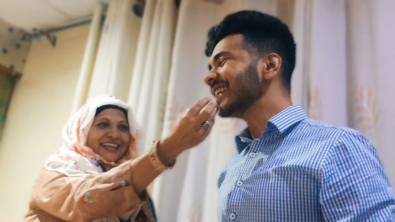Maman laughing as she shares a sweet with her son on a happy day at home